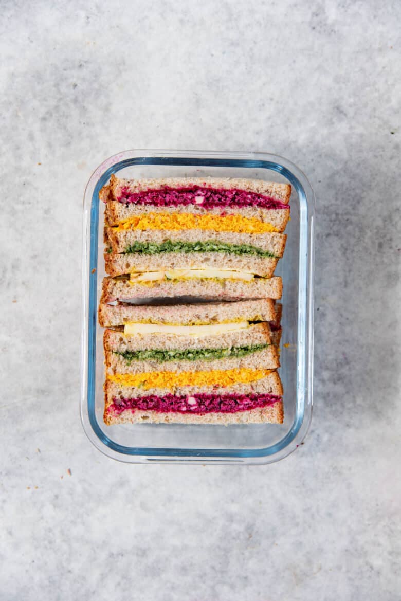 A four decker rainbow sandwich inside a lunch box.