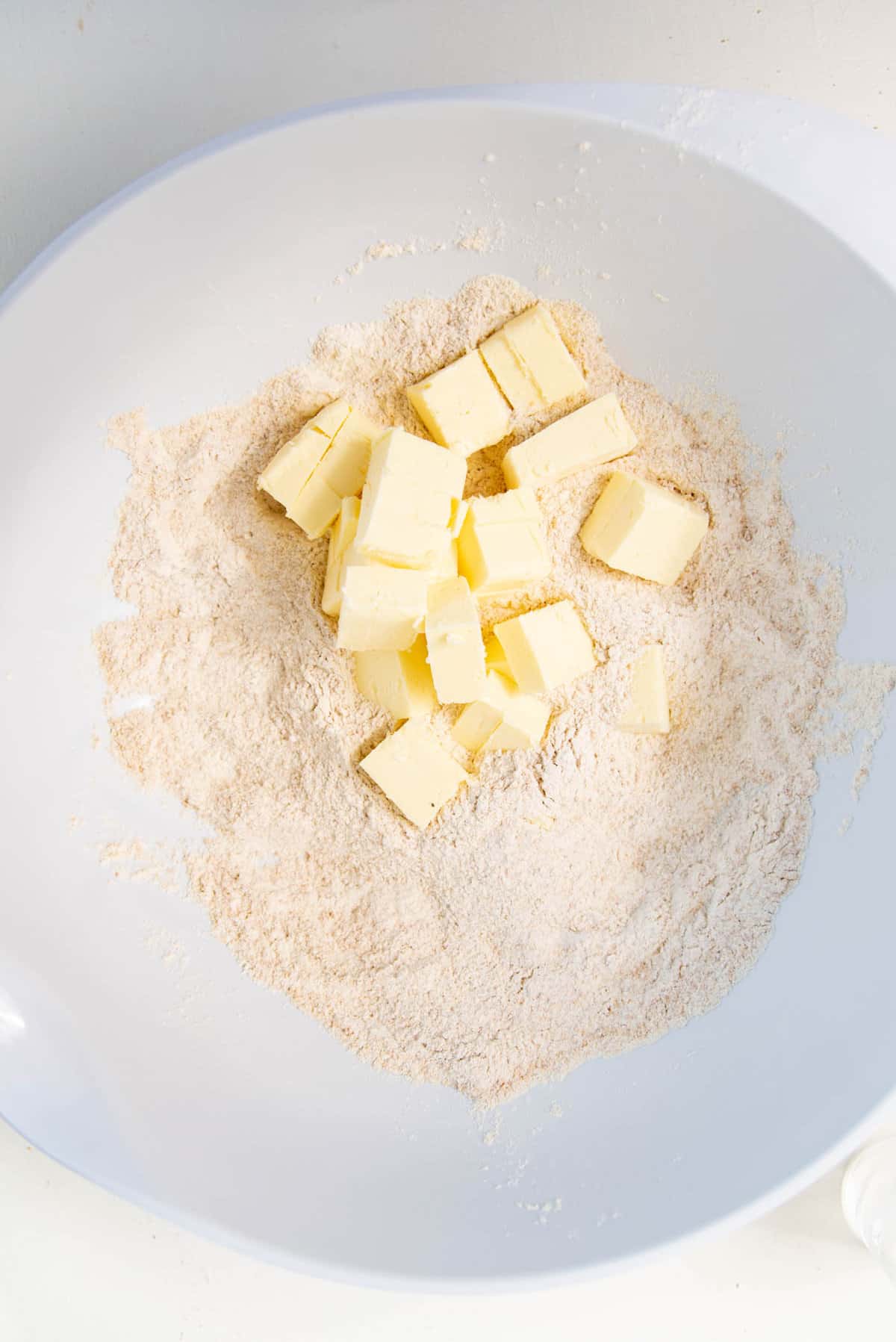 Cubed cold butter added to the dry ingredients in the bowl.