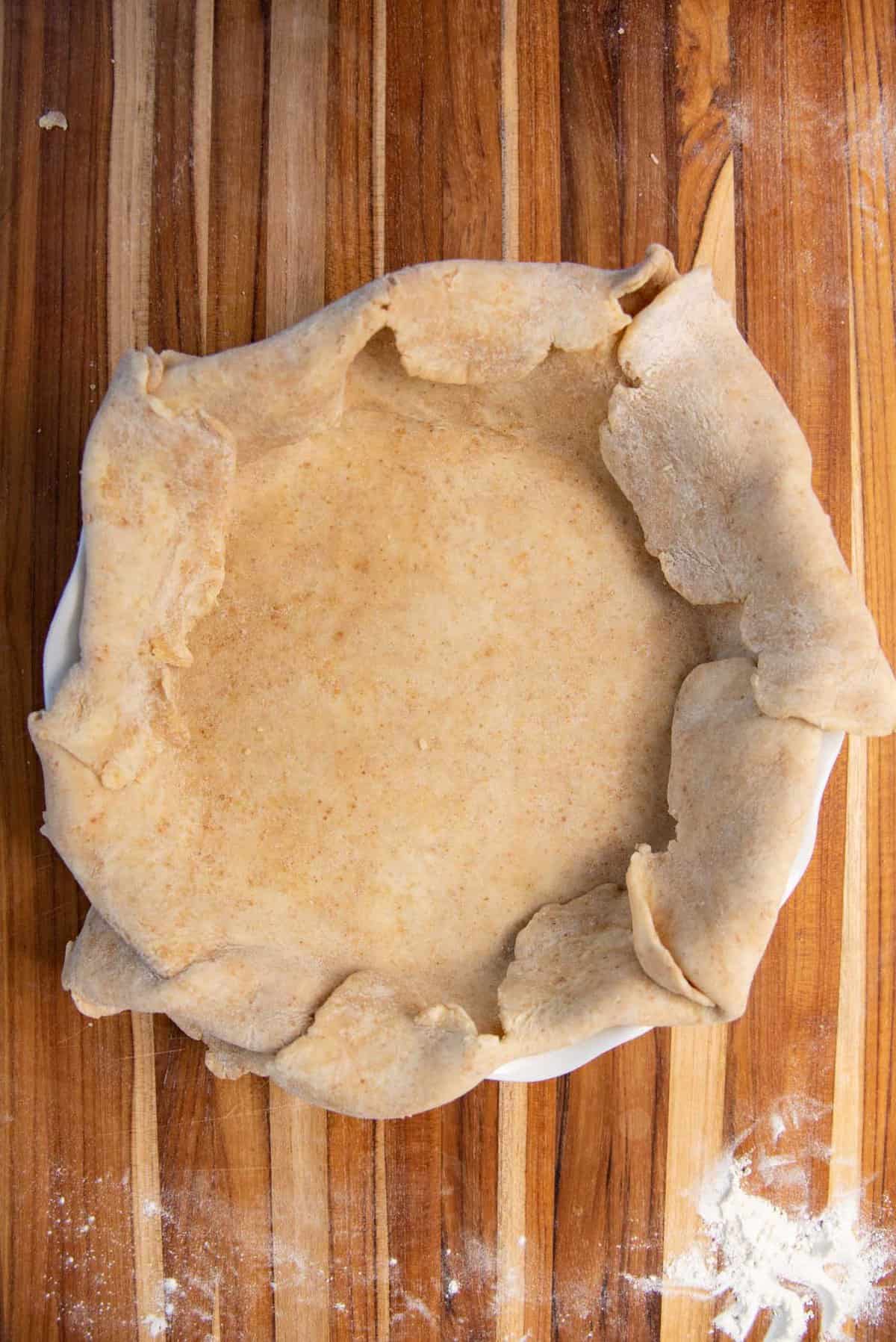 The rolled out pie dough in a pie dish.
