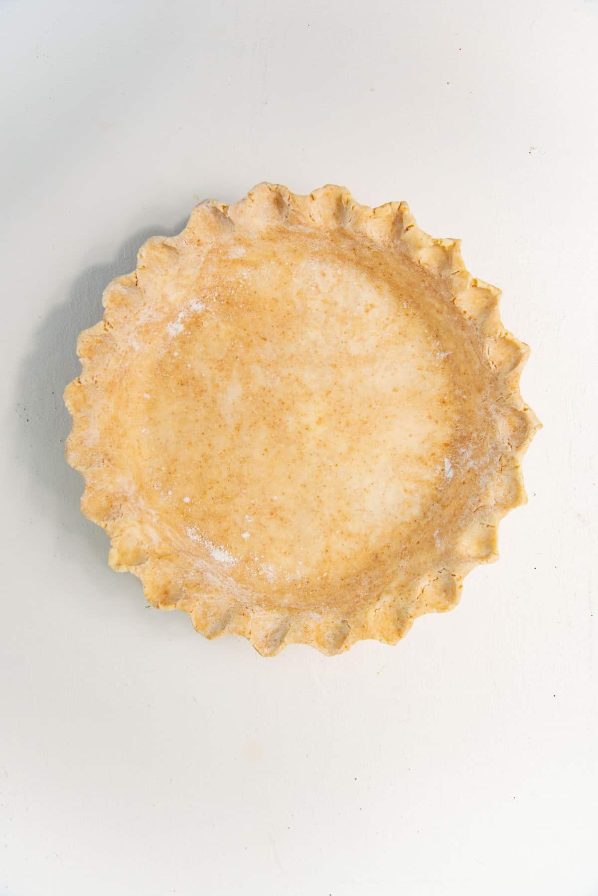 Graham flour pie dough crust in a pie plate with fluted edges.