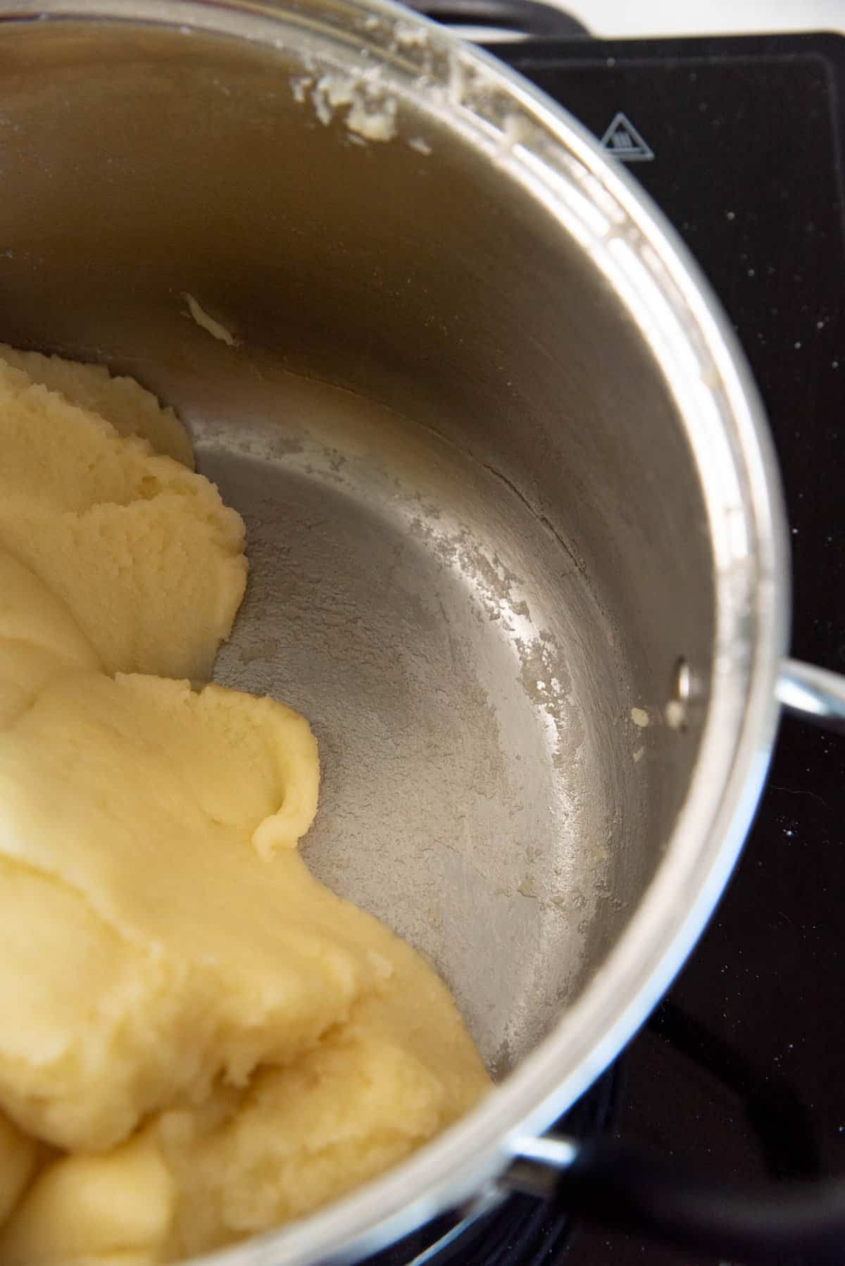 An image showing a thin dough film on the bottom of the saucepan, which is an indication to look for when making choux pastry.