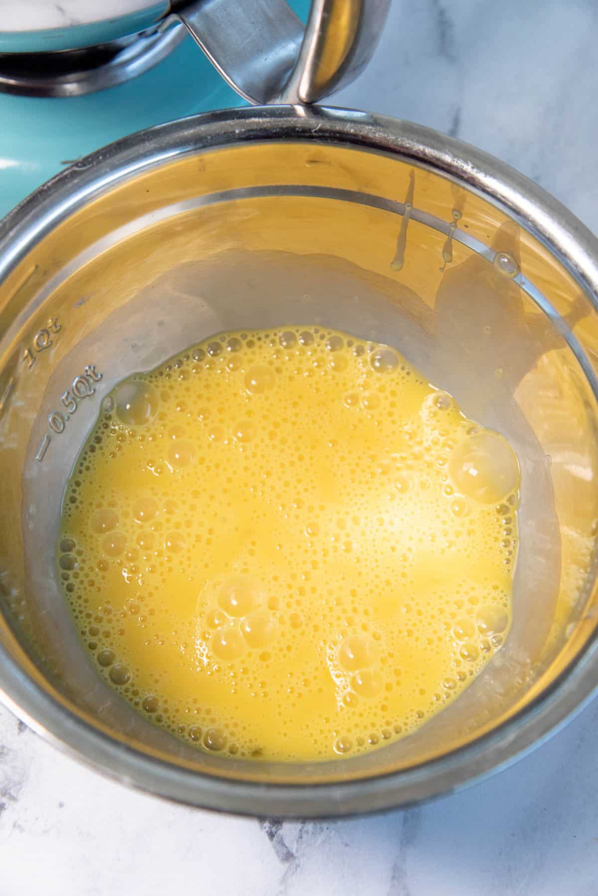 Eggs whisked in a metal bowl.