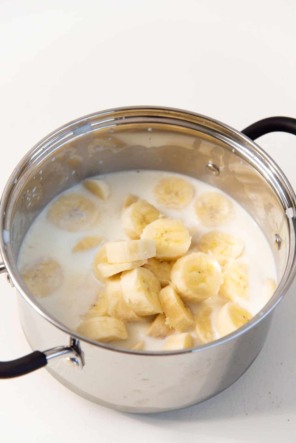 Sliced bananas in a saucepan with milk.