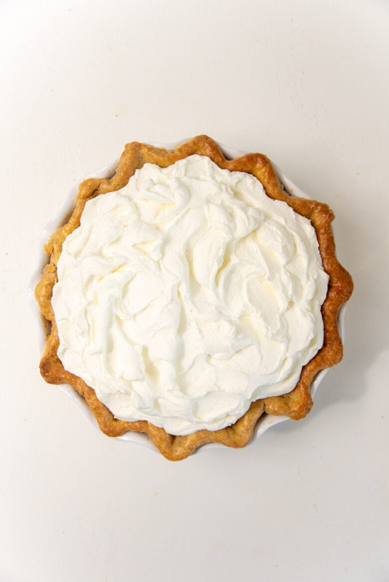 Overhead view of the banana cream pie with the whipped cream spread on top.