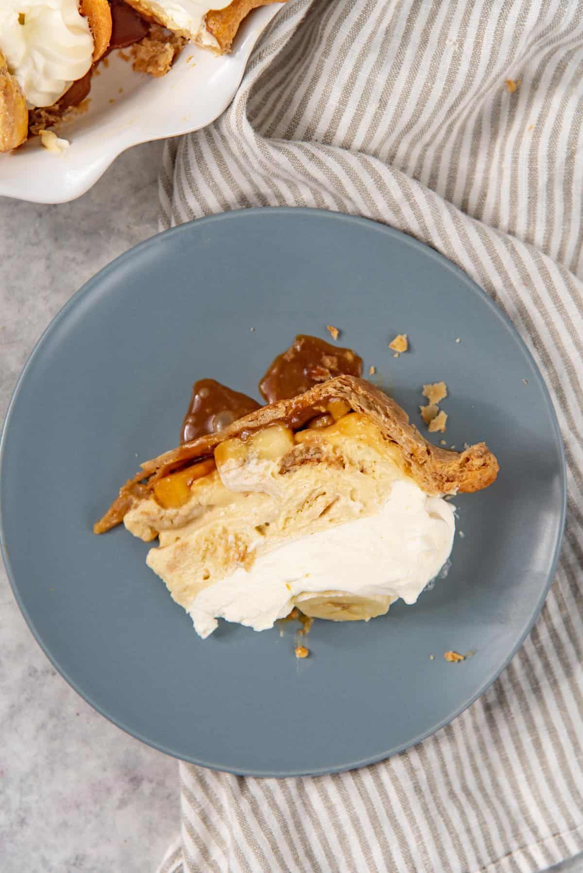 An overhead view of the banana cream pie slice, laid on its side, showing the caramel layer, banana layers, layers of banana pudding with wafers and whipped cream topping.