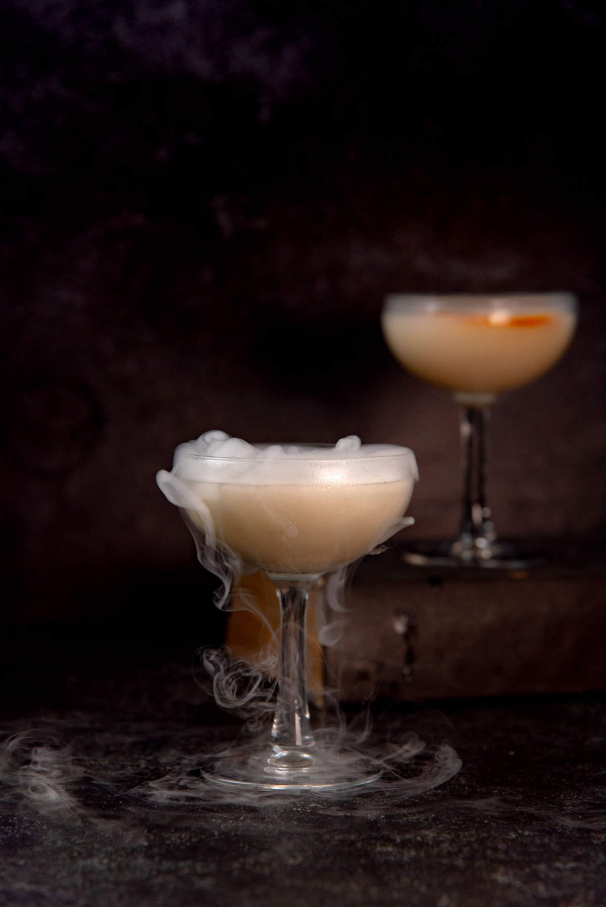 Unicorn blood cocktail for halloween, with silvery white shimmery swirls, and smoke from dry ice.