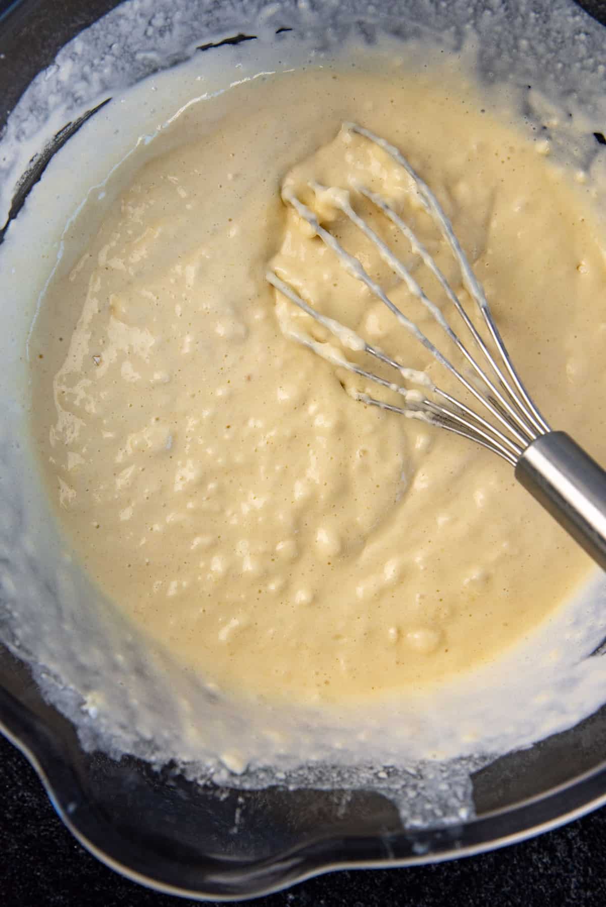 A close up of the pancake batter after mixing with the whisk, showing the lumpy consistency.