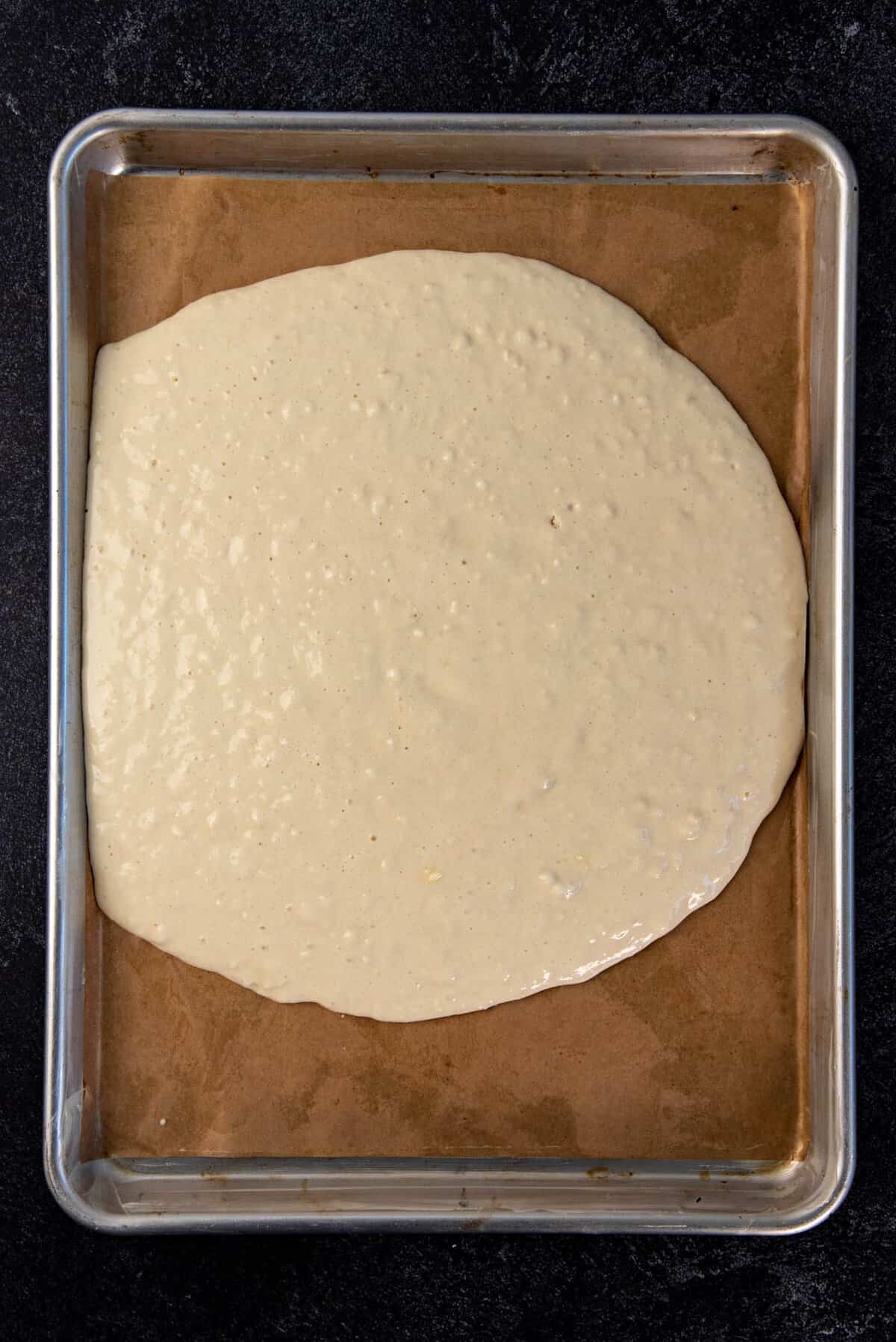 The pancake batter poured into the center of the prepared half sheet pan.
