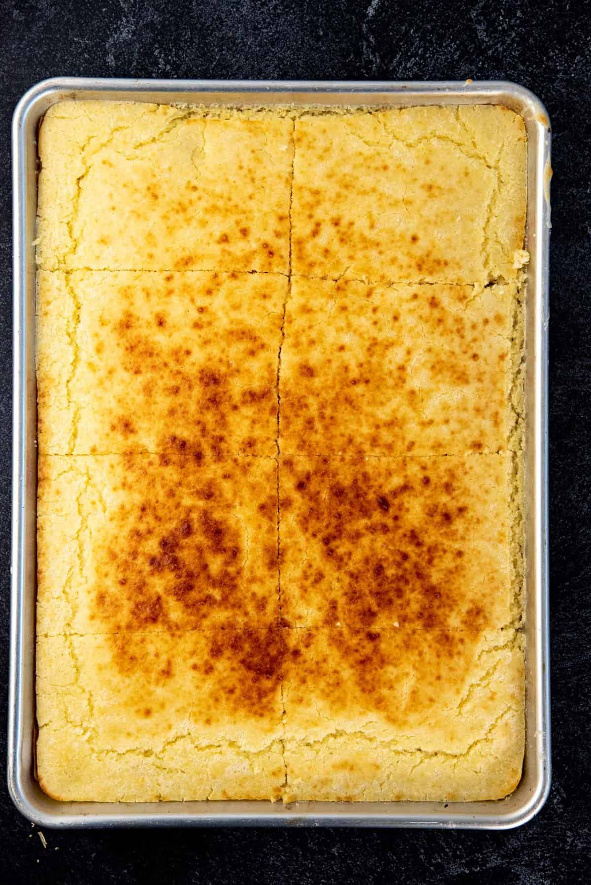 An overhead view of the sheet pan pancakes, after broiling to show the caramelized surface and then cut into 8 portions.