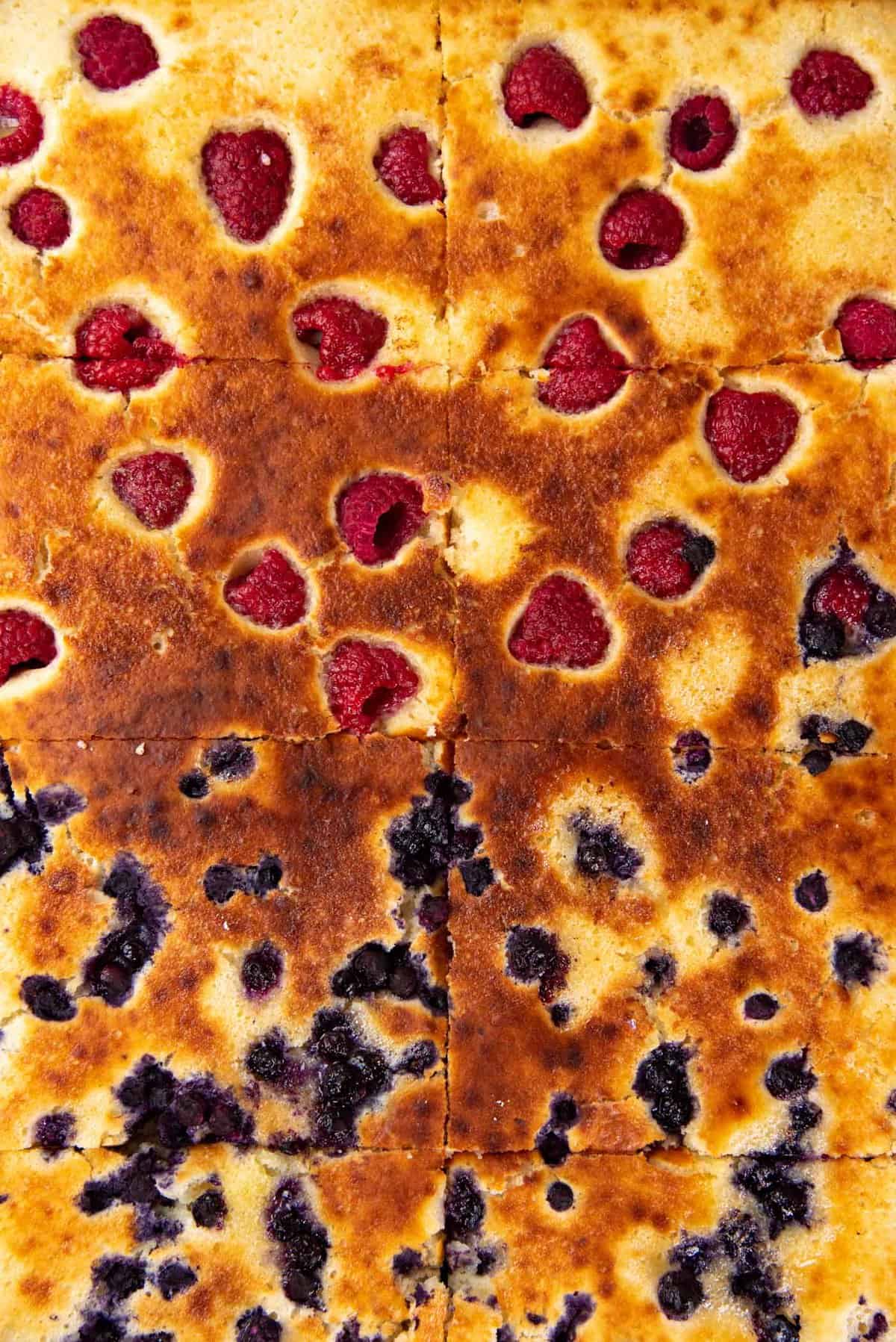 An overhead view close up of the raspberry and blueberry sheetpan pancakes, cut into slices.