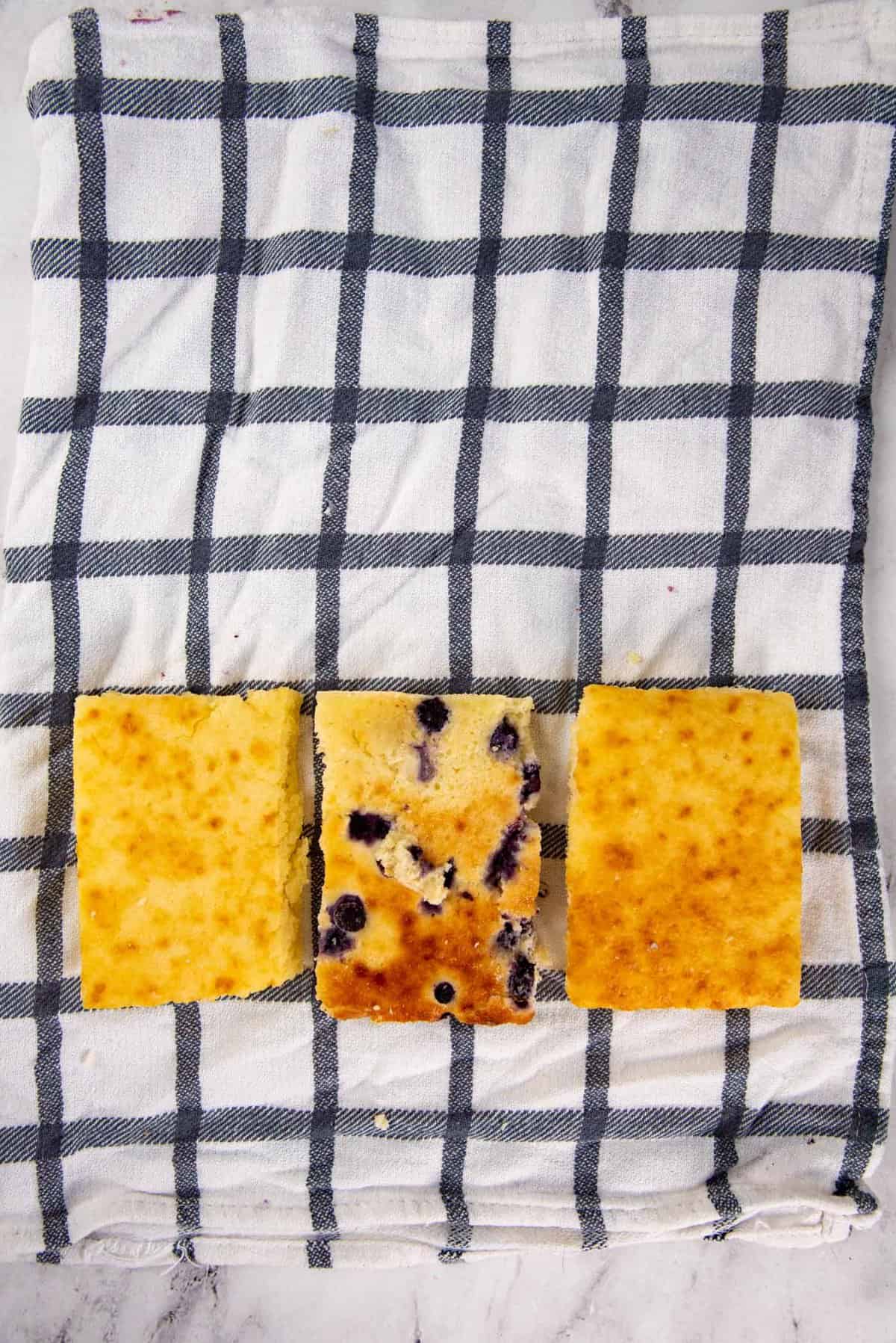 Showing how to reheat frozen pancakes properly - An image of 3 pieces of frozen pancakes, placed on a cloth napkin with water misted.