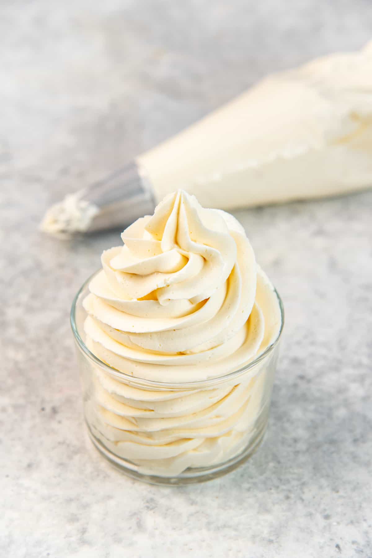 Vanilla buttercream frosting that has been piped into a small bowl, to show the consistency.