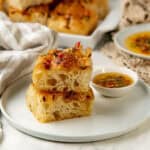 Close up focaccia slices with airy, open crumb, served on a white plate.