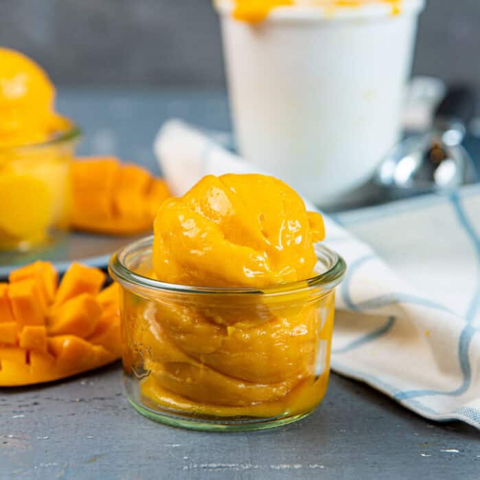 Close up of mango sorbet in a glass jar showing the silky smooth texture.
