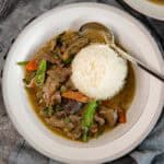 Green curry beef served with white rice and a spoon in a plate.