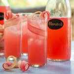 Close up of pink rhubarb drink in glasses garnished with rhubarb ribbons.