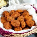 Deep fried dal vada with crispy, golden brown exterior placed in a woven basket.