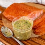 Honey dill mustard sauce in a glass jar with salmon gravlax in the background.