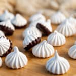 Classic meringue cookies and chocolate dipped meringue cookies on a wooden surface.