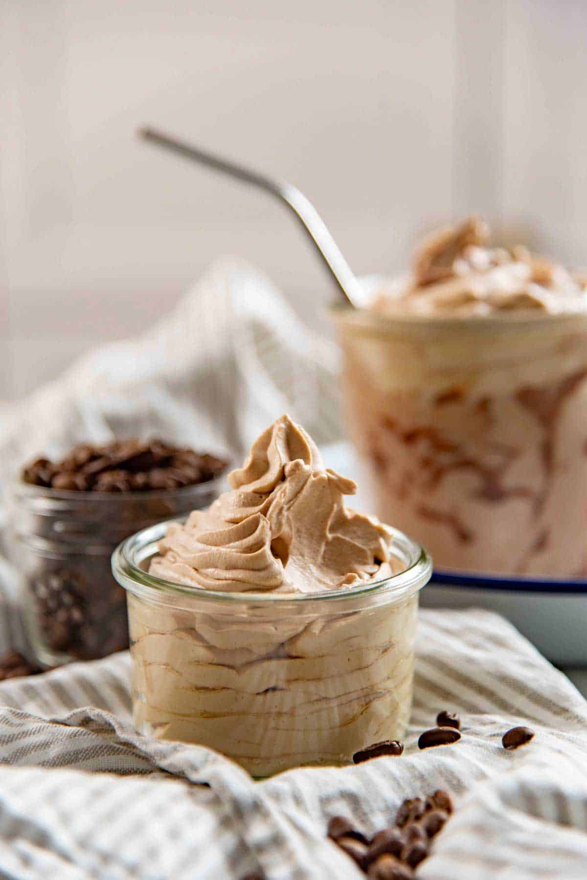 A scoop taken out of the creamy coffee whipped cream piped into a small glass jar.