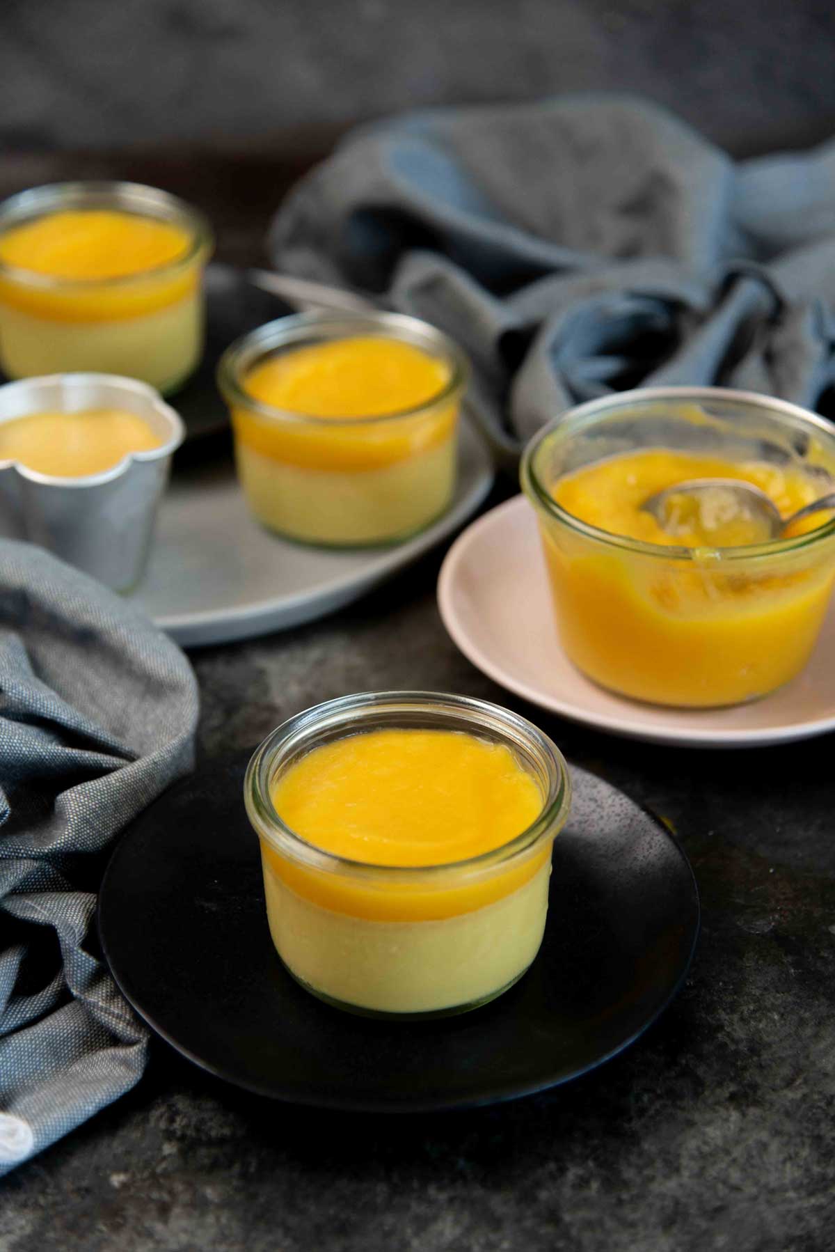 Mango panna cotta in a small glass dish topped with a layer of shiny mango gel topping.