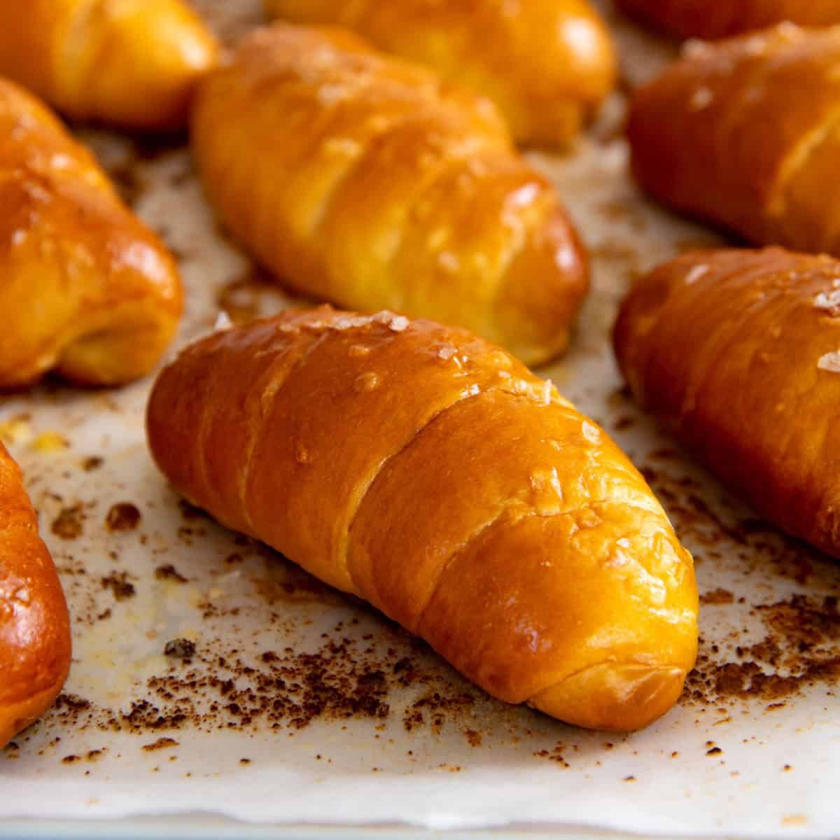 Close up of freshly baked golden brown shio pan with flaky salt on top on a parchment paper.
