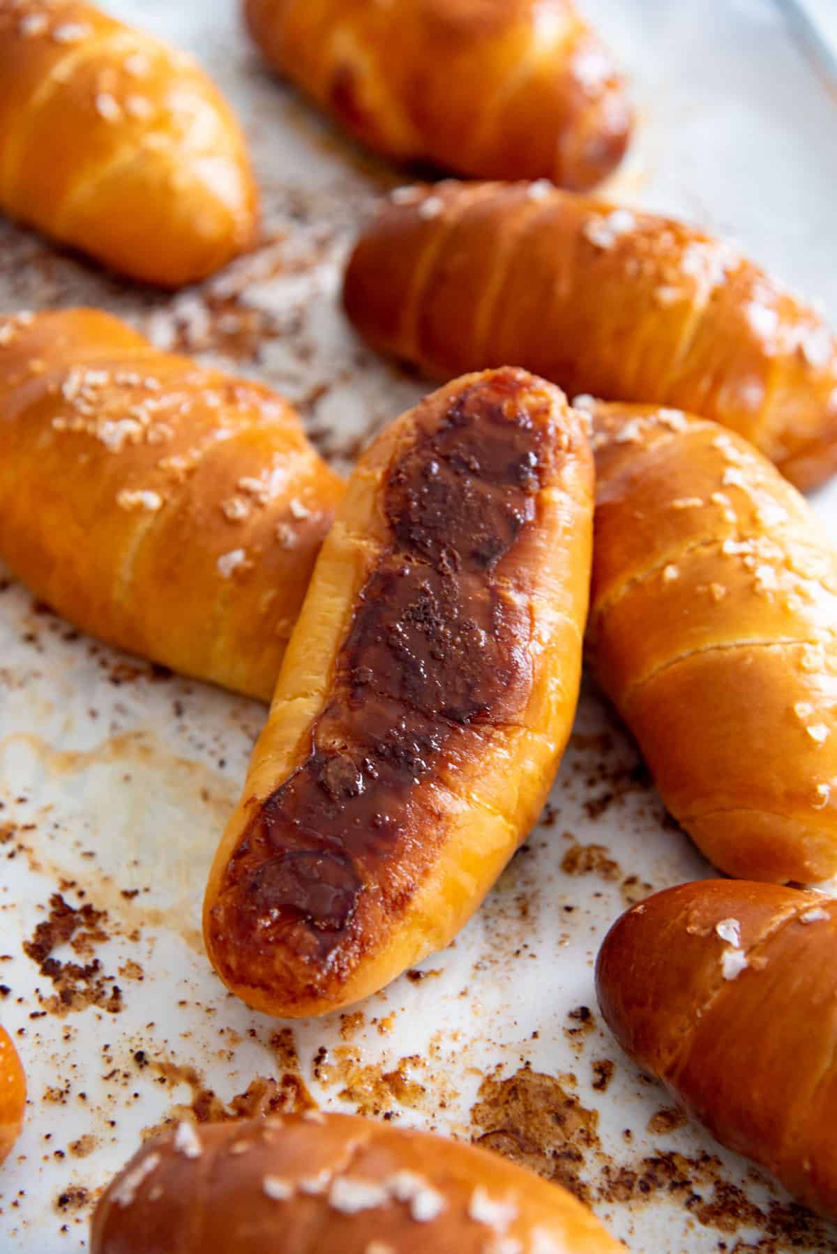 Freshly baked salt bread on a parchment paper with one bread roll turned over to show the crispy bottom.