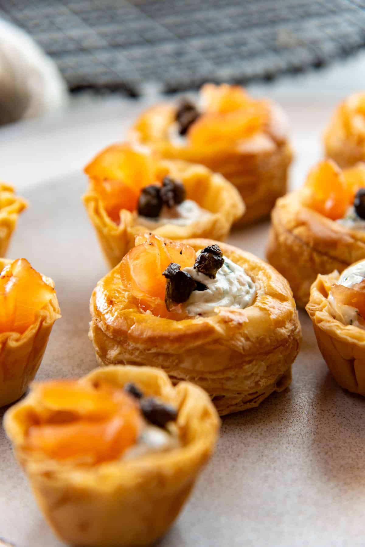Smoked salmon canapes served in mini puff pastry tarts on a white plate.