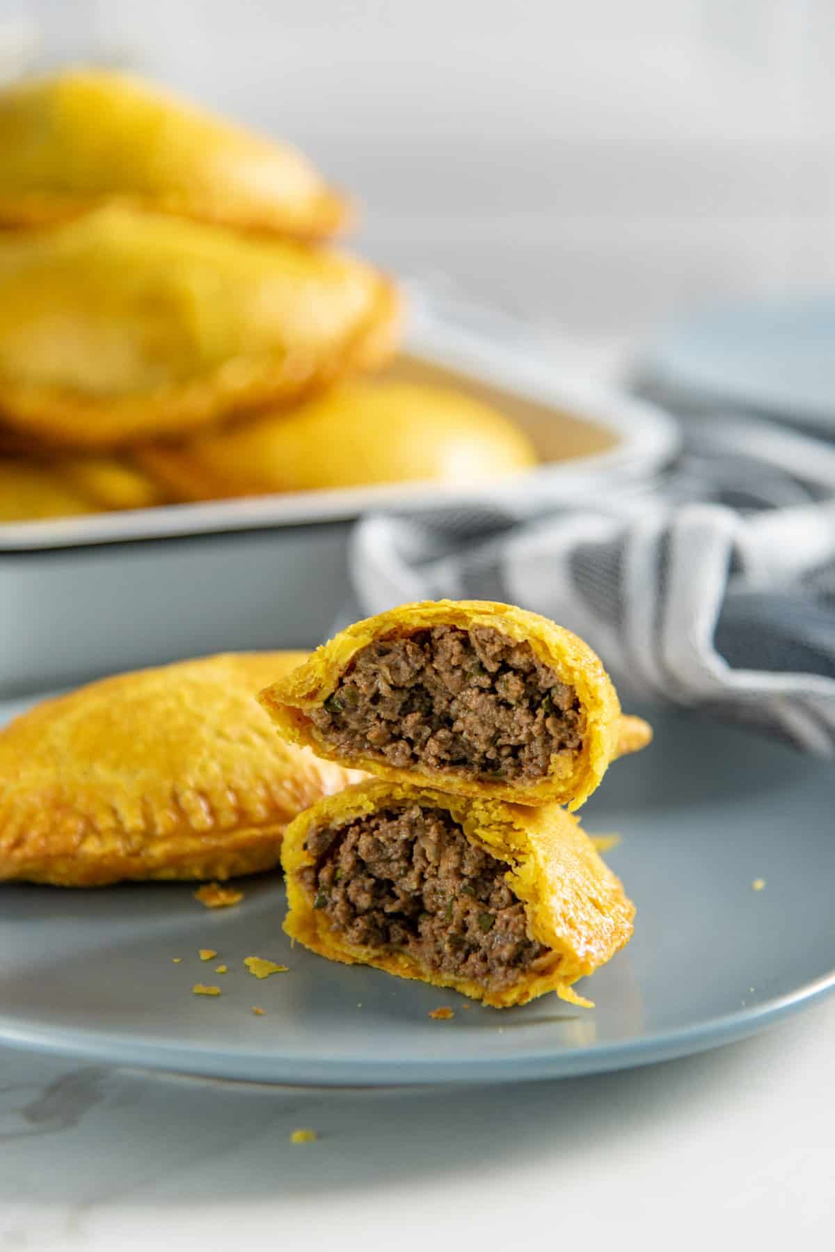Close up of a curried beef patty broken in half to show the juicy, spicy ground beef filling in the middle.