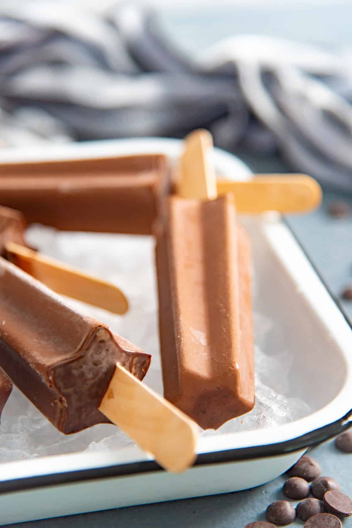 Close up of a star-shaped, creamy chocolate fudgesicle placed on top of crushed ice.