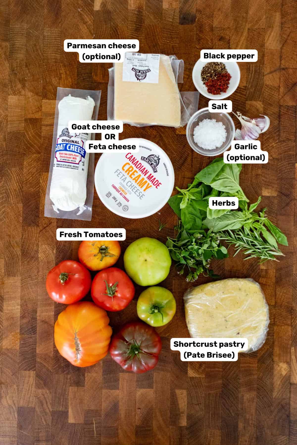 Labeled ingredients to make tomato tart on a wooden surface.