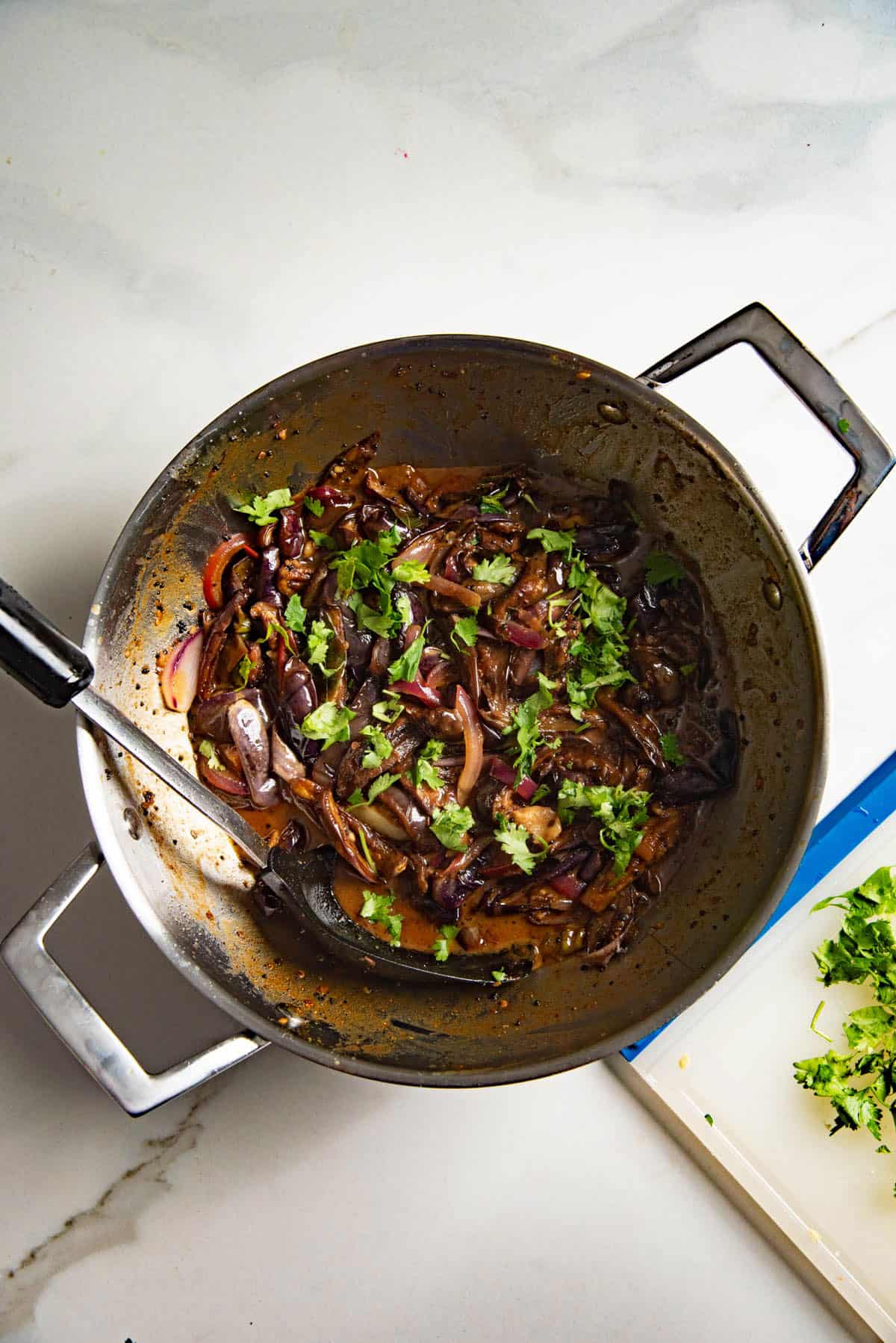 Overhead view of Sri Lankan brinjal curry in a small saucepan topped with some chopped cilantro.