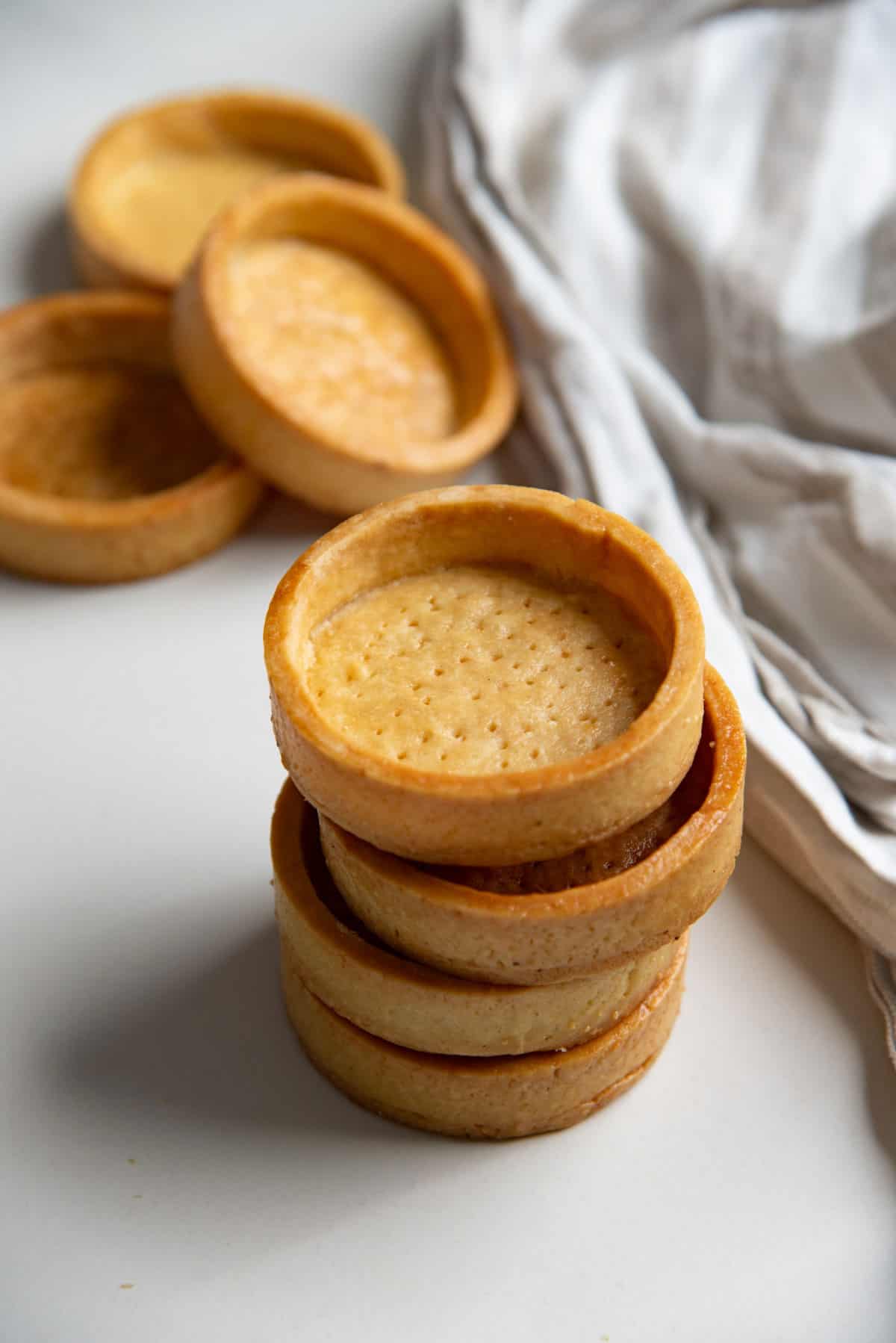 Four mini tart crusts made with pâte brisée stacked on top of each other.