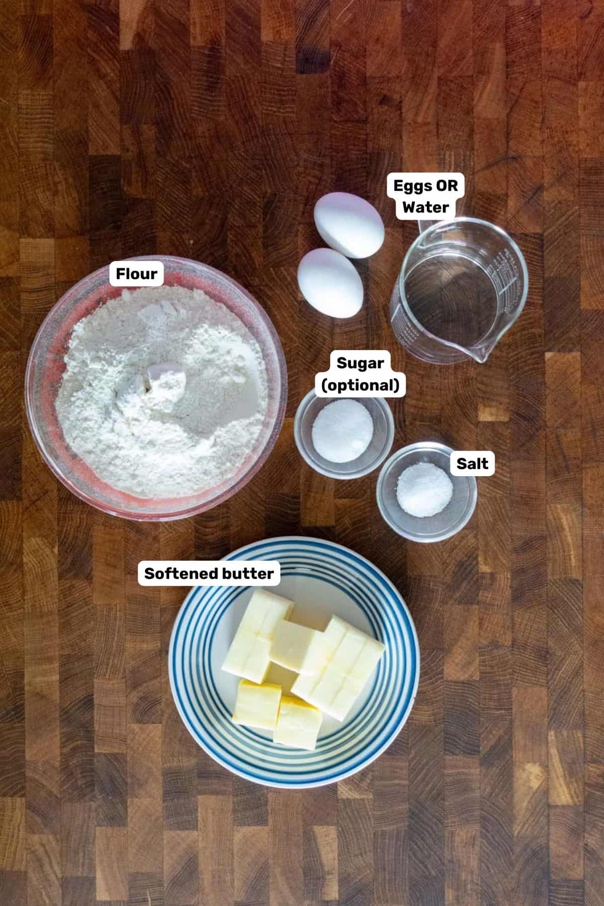 Labeled ingredients needed to make shortcrust pastry (pâte brisée) on a wooden surface.