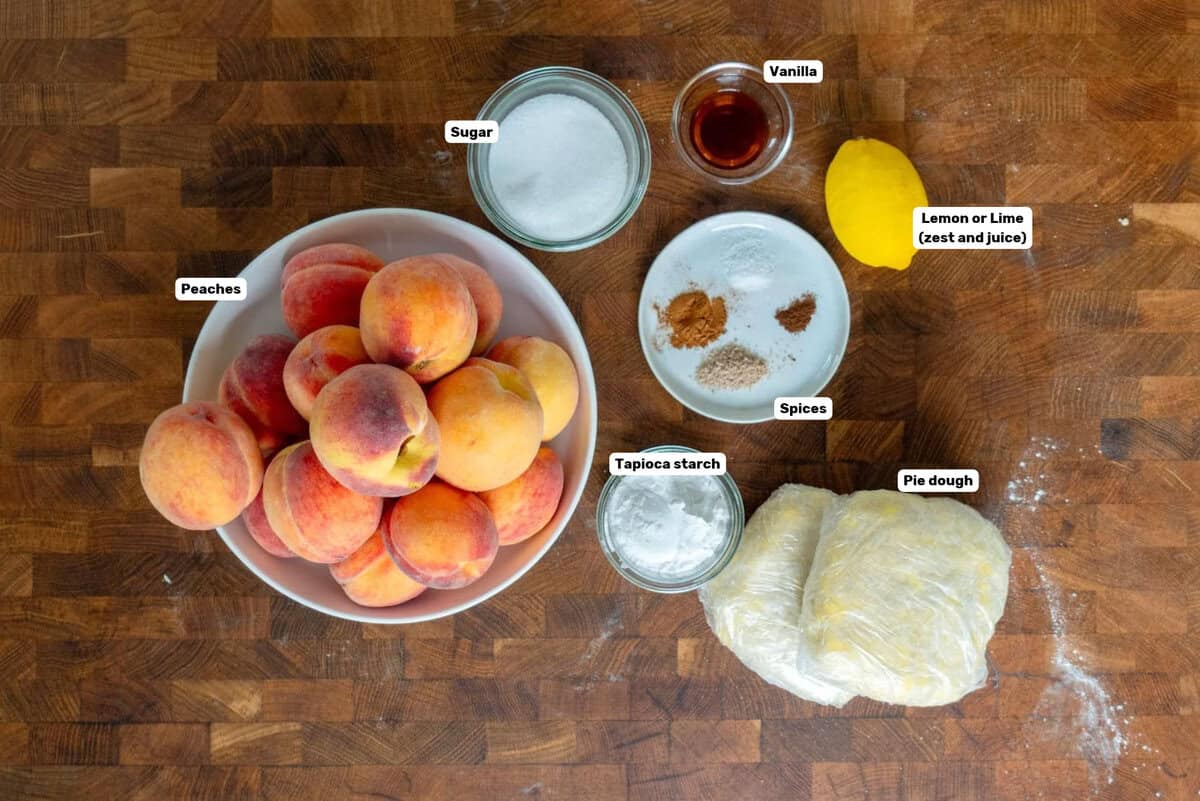 Labeled peach pie ingredients on a wooden surface.