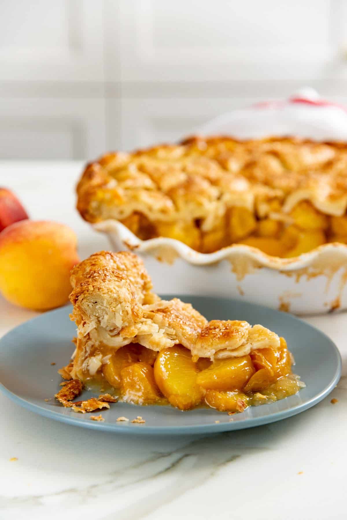 Side view of a slice of peach pie, showing the juicy peach pie filling spilling out.
